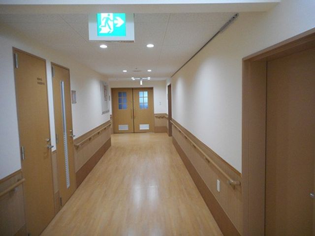 手すりのある廊下 廊下 安全に配慮された手すり付きの長い通路です。落ち着いた色合いで歩きやすい設計になっています。