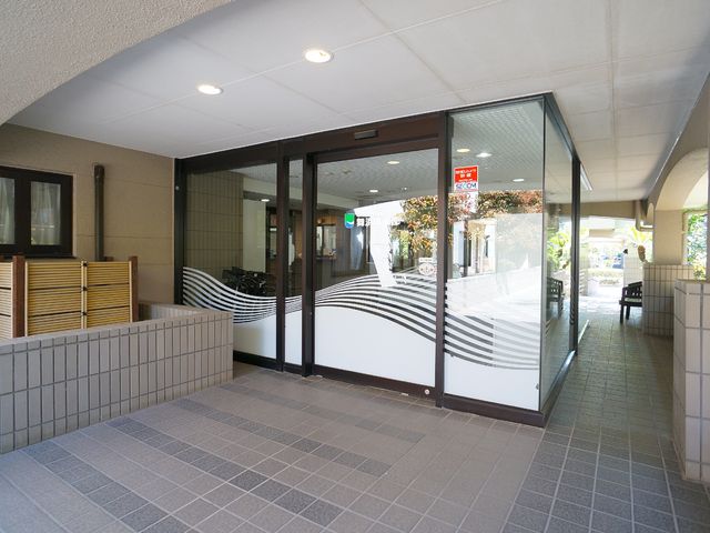 明るいエントランス通路 玄関 ゆったりとした通路と自動ドアが設置され、清潔感のあるエントランスを備えた施設です。訪れる方々を温かく迎え入れる設計になっています。
