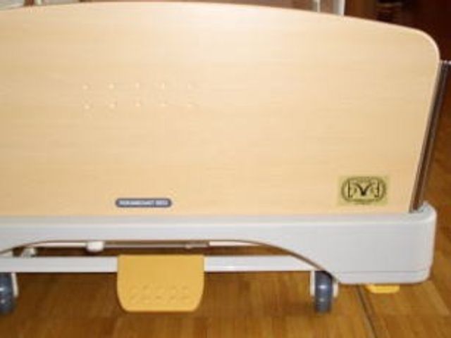 ベッドの足元 居室   木目調のベッドの足元が写っており、落ち着いた雰囲気です。就業を考える方は、居室の様子をイメージしやすいです。