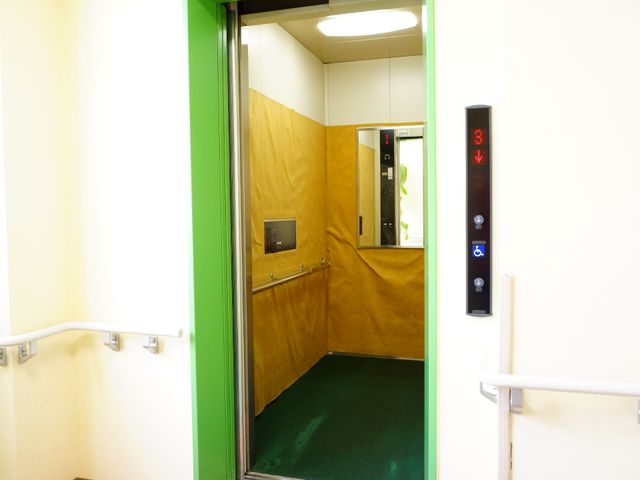 手すり付き廊下とエレベーター エレベーター 廊下に手すりが設置され、エレベーターには大きく見やすい階数表示があります。安全と利便性の配慮が行き届いた環境が整っています。