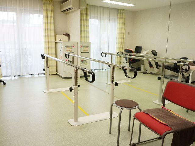 機能訓練室の設備 歩行訓練用バー 日光の差し込む明るい訓練室で、様々なリハビリ機器を使い、利用者様の体力維持・向上をサポートします。