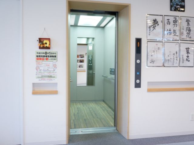 清潔なエレベーター前 エレベーター 壁には掲示物が整然と飾られ、エレベーターは手すりがついており安全に配慮されています。バリアフリー設計で、誰もが快適に移動できる空間づくりに努めています。