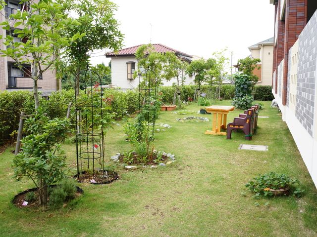 手入れされた緑豊かな庭 裏庭 手入れの行き届いた緑あふれる中庭では、居住者が潤いと安らぎの時間を過ごされています。木々や花々に囲まれた空間は、心地よい憩いの場を提供しています。