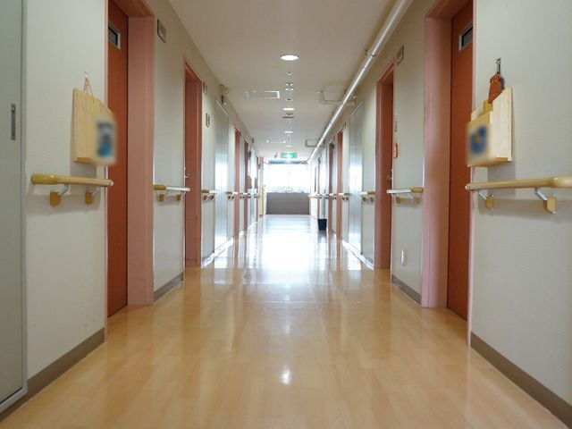 明るく綺麗な施設の廊下 通路 床が光る温もりのある廊下で、手すりが整備されているため、安心して歩行できる環境です。