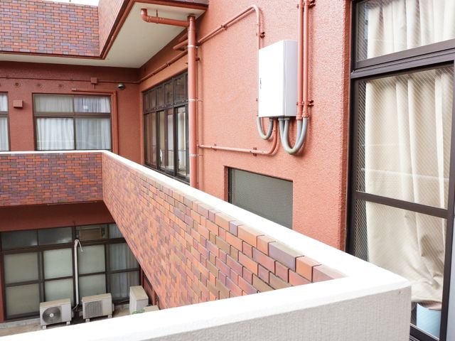 赤い外壁の建物のバルコニー バルコニー 清潔に保たれたバルコニーより、穏やかな日々が想像できます。