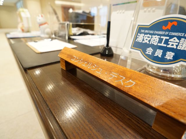 カウンターに置かれたネームプレート コンシェルジュ・デスク ゆったりとしたカウンターには温かみのある木製のネームプレートが置かれ、明るく落ち着いた雰囲気を感じさせます。