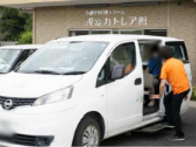 施設の送迎サービス 外観 スタッフが利用者の方を車から親切に誘導しています。温かみのあるサポートが特徴です。