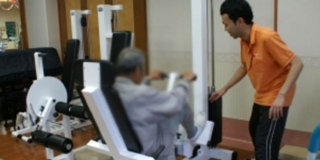 機器を使って訓練する様子 機能訓練室 明るく開放的な空間で、専門スタッフが丁寧に指導している訓練の様子です。安心して日々のリハビリに取り組める環境を提供しています。