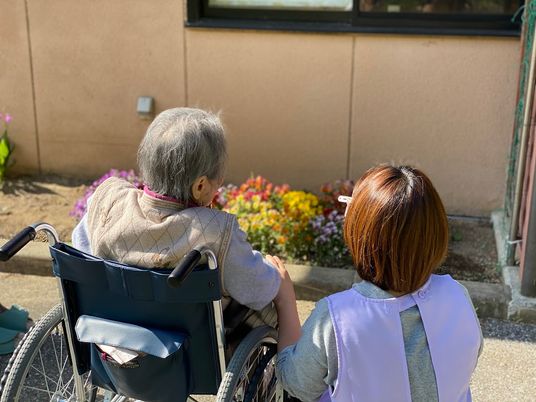 花を見つめる利用者とスタッフの後ろ姿