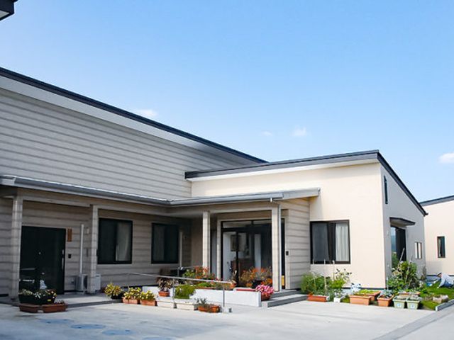 明るい外観の居室 外観 ゆったりとした造りの居室があり、窓から自然光が差し込んでいます。花々に囲まれた入口が、温かな印象を与えています。