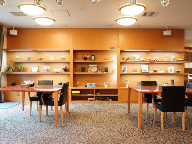 温かみのある共有スペース リビング 広々としたダイニングルームは、くつろぎながら食事やお話が楽しめる設計になっており、陶芸作品などが飾られた棚が空間に彩りを加えています。