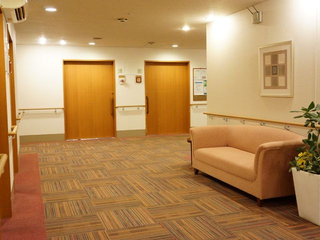 廊下と休憩スペース 共用廊下 温かみのある色合いのソファが設置され、落ち着いた雰囲気の休憩スペースがあります。ゆったりとした時間を過ごしながら、くつろぎのひと時を提供しています。