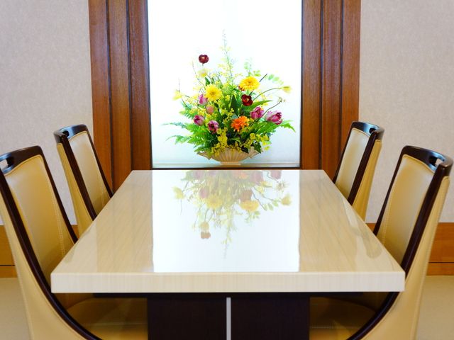 明るい居室のテーブル 談話スペース きれいに整えられた居室には、食事や憩いの時間を彩る花が飾られています。温かみのある空間でのひとときをお過ごしいただけます。