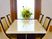 談話室は、4人用のテーブルと椅子が置かれている。真新しいテーブルには、壁際の花の置物が反映されている。