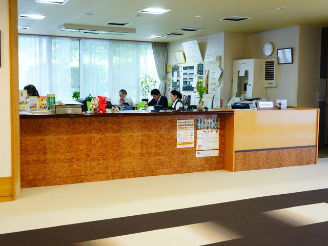 光が差し込む明るいフロント 受付 笑顔で対応するスタッフがいる、温かみのある受付カウンターです。清潔感のあふれる環境は、来訪者に安心感を与えます。