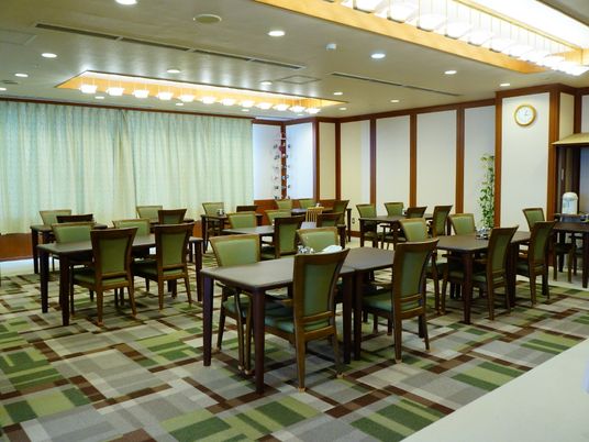 食堂は2人掛けのテーブルと椅子が並べられて、複数セット置かれている。床は段差がなく、チェックに似たデザインをしている。