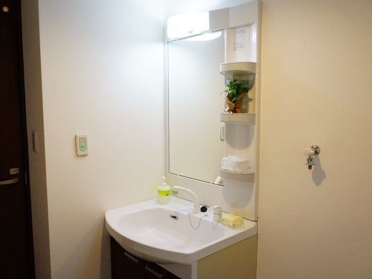 施設の写真 洗面台は、周りを白で統一された清潔感のあるデザインとなっている。壁に呼び出しボタンがあるので、安心して利用出来る。