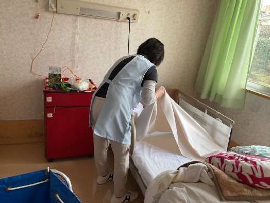 居室でベッドを整える職員  