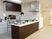 サムネイル 調理台が広く機能的なカウンターキッチンで、大きな換気扇が設置されている。濃い茶色のシックなデザインになっている。