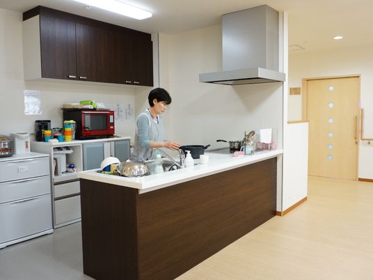 調理台が広く機能的なカウンターキッチンで、大きな換気扇が設置されている。濃い茶色のシックなデザインになっている。