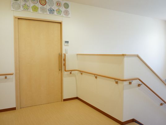 階段から二階の廊下にかけて、転倒防止の手すりが連続して付いている。個室に入るドアは大きく、スライド式になっている。