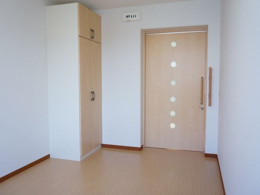 居室の入り口はスライド式で大きく、車椅子でも出入りが容易。入り口の脇には大きな棚があり、木製で暖かな印象。