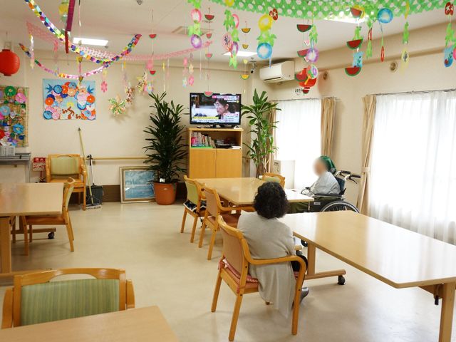 飾り付けされた明るい食堂 共有スペース 心地よい装飾が施された食堂で、利用者同士がくつろぎながら過ごせる環境が整っています。テレビを見たり、おしゃべりを楽しんだり、日々の憩いの場となっています。