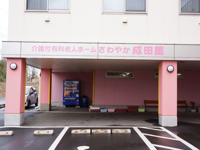 ピンクの入口と自動販売機 駐車場 ゆとりのあるエントランスには、休憩ができるベンチと自動販売機が備えられており、待ち合わせにも適しています。