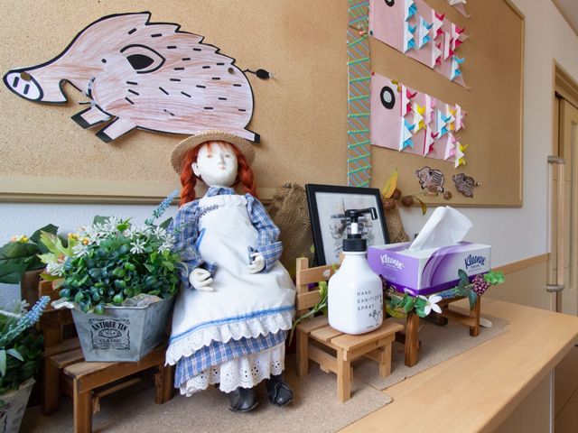 廊下の装飾と人形 飾り 廊下に色とりどりの装飾があり、和やかな雰囲気を醸し出しています。こちらで働くと毎日温かい気持ちになれそうです。