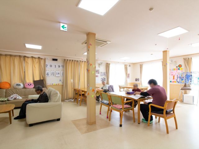 共有スペースの日常風景 食堂 利用者がリラックスして読書を楽しむ、居心地の良いラウンジです。明るく開放感のある設計で、日々のコミュニケーションの場となっています。