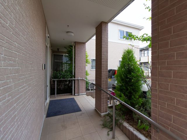 居住エリアのベランダ風景 玄関ポーチ ゆったりとしたベランダは、緑に囲まれており、屋外での穏やかなひとときを過ごすのに適しています。