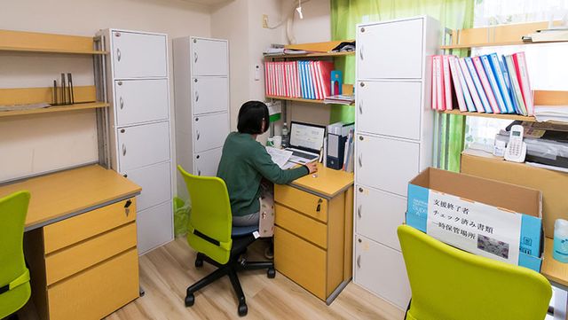 明るい居室デスクスペース 居室 整理されたデスクで作業に集中するスタッフの様子をご覧いただけます。快適な居室環境が整っています。