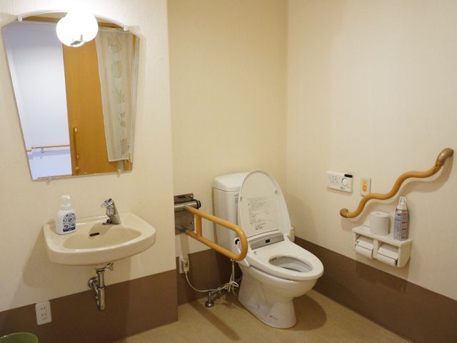 バリアフリー設計のトイレ トイレ 安全で清潔感のあるトイレ環境が整っており、手すりや緊急時の呼び出しボタンも設置されています。