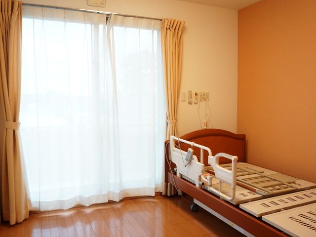 明るい居室の一角 居室 ゆったりとした居室は、快適な木目調のベッドと大きな窓で構成され、温もりが感じられる空間です。