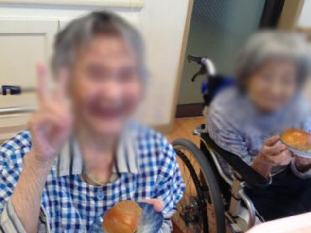 和やかな食事風景 ダイニングルーム 楽しげに食事をしている様子が見られます。介護施設での温かな生活風景を感じられます。