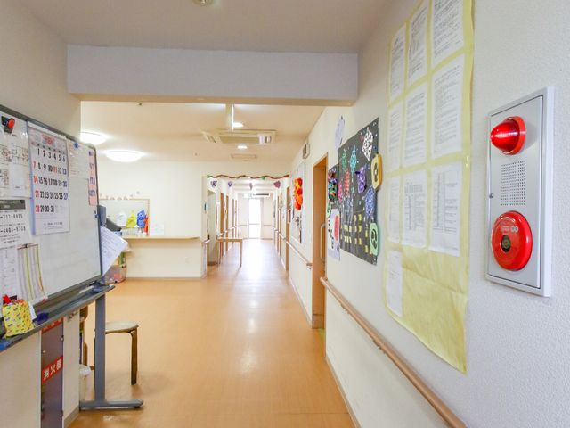 廊下の注意書き散布 共有スペース 壁沿いに掲示物が配置され、通路の清潔感が保たれた空間です。ゆったりとした廊下は、作業もしやすい構造となっています。