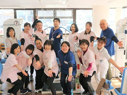 笑顔のスタッフが並ぶ機能訓練室