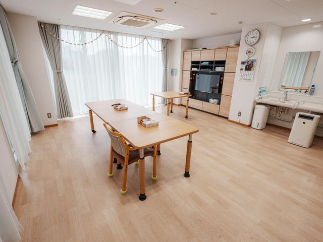 窓辺の明るい空間 多目的室 広々とした明るい部屋では、自然光が差し込み、快適な作業環境を提供しています。テーブルは、用途に応じた活動がしやすい配置になっています。