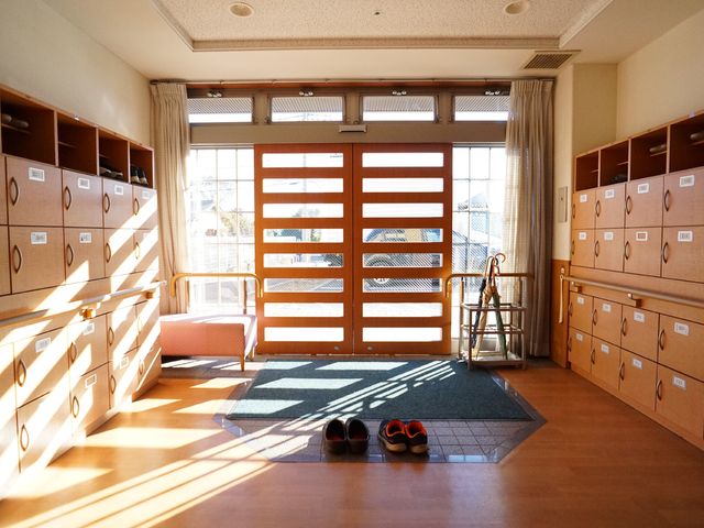 エントランスの明るい空間 玄関 陽光が差し込む温かみのあるエントランスです。高い天井と木の温もりが感じられる収納棚が配置されており、心穏やかに過ごせる空間をご提供しています。