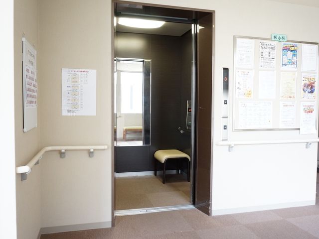 エレベーター前掲示物 エレベーター 広々とした通路とエレベーター、壁には掲示物があり情報共有に役立っています。明るく清潔感のある環境をぜひ体感してください。