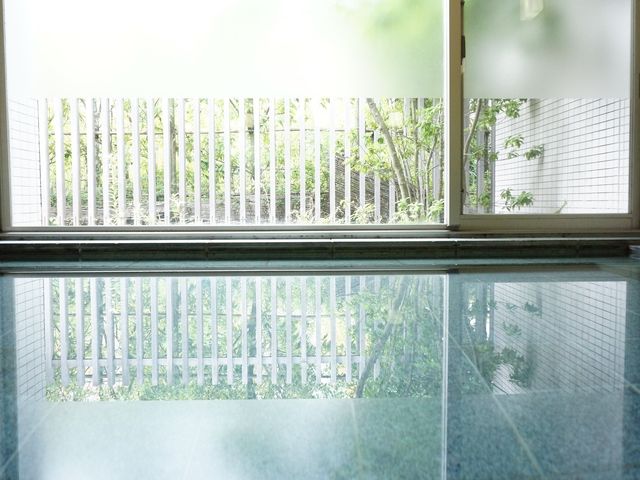 緑に囲まれた明るい室内 大浴場 窓から自然光が差し込み、爽やかな中庭の緑が目に優しいです。日々の暮らしにここで癒しのひとときをお過ごしいただけます。