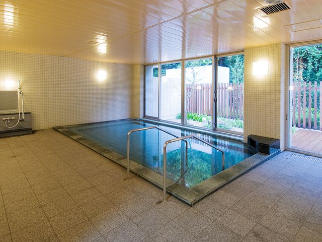 清潔なバリアフリー浴室 大浴場 床に段差がなく、手すりが設置された広々とした浴室です。窓から自然光が差し込み、開放的な空間でリラックスできます。