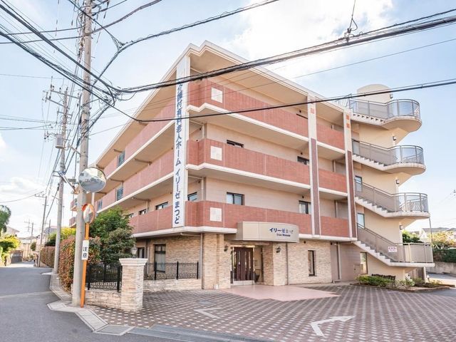 静かな街並の建物正面 外観 落ち着いた住宅街に佇む明るい施設外観です。きれいな外壁と広い敷地が快適な環境を提供しています。