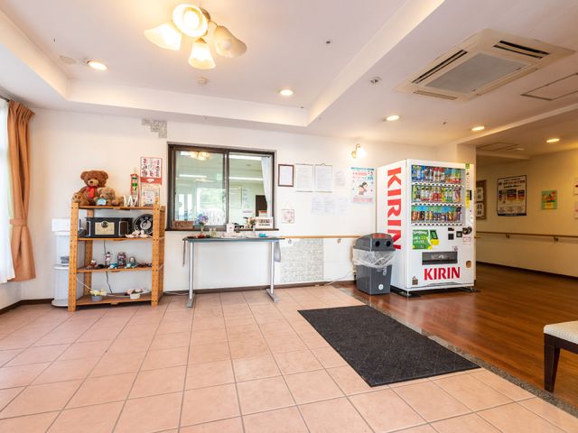 快適な居心地の休憩室 玄関 くつろぎ空間には飲み物がいつでも利用可能な自動販売機が備わっており、壁には様々な掲示物で日々の生活がサポートされています。