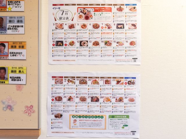 メニュー掲示の壁面 展示物 壁には美味しそうな日々の献立を示すメニュー表を掲示しており、栄養バランスに心を配った料理の提供を実践しています。