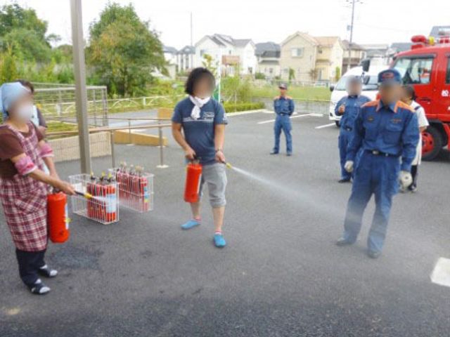 消火訓練実施する人々 防災訓練 皆で協力して消火訓練を行っている安全に細心の注意を払う環境です。チームワークを大切にする職場で力を発揮しませんか。