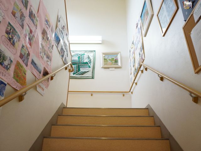 壁に装飾のある階段 階段 手すりがついた明るく清潔な通路。壁には彩り豊かな掲示物が飾られ、温かみのある雰囲気を作り出しています。
