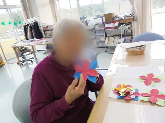 手工芸活動の様子 多目的室 自然光が差し込む空間で、手工芸活動に参加できます。参加者は色鮮やかな作品を制作中です。