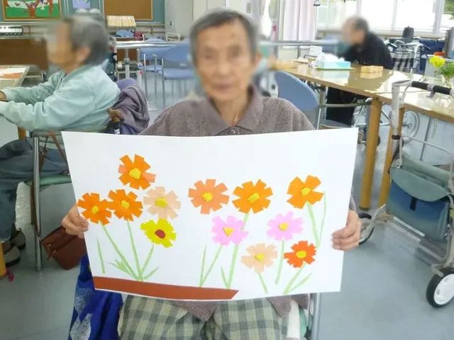 作品を持つ人のテーブル 多目的室 明るい多目的室では、創作活動を楽しむことができます。お互いに作品を見せ合い、交流の機会にもなっています。