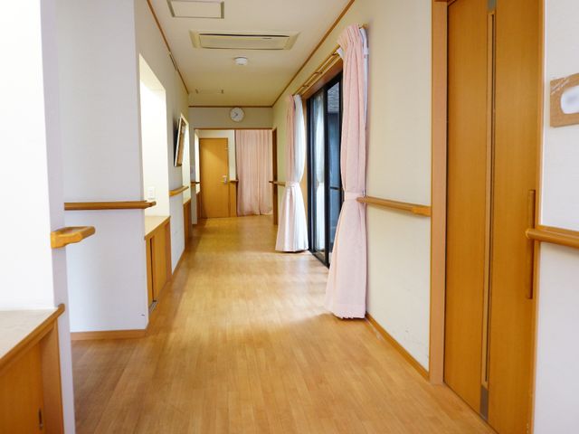 廊下の手すりと木目調のドア 明るくスッキリとした廊下 明るく清潔感のある廊下は、手すりが設置されており、歩行に自信がない方にも安心です。木目のドアも温かみがあり、落ち着いた雰囲気を醸し出しています。